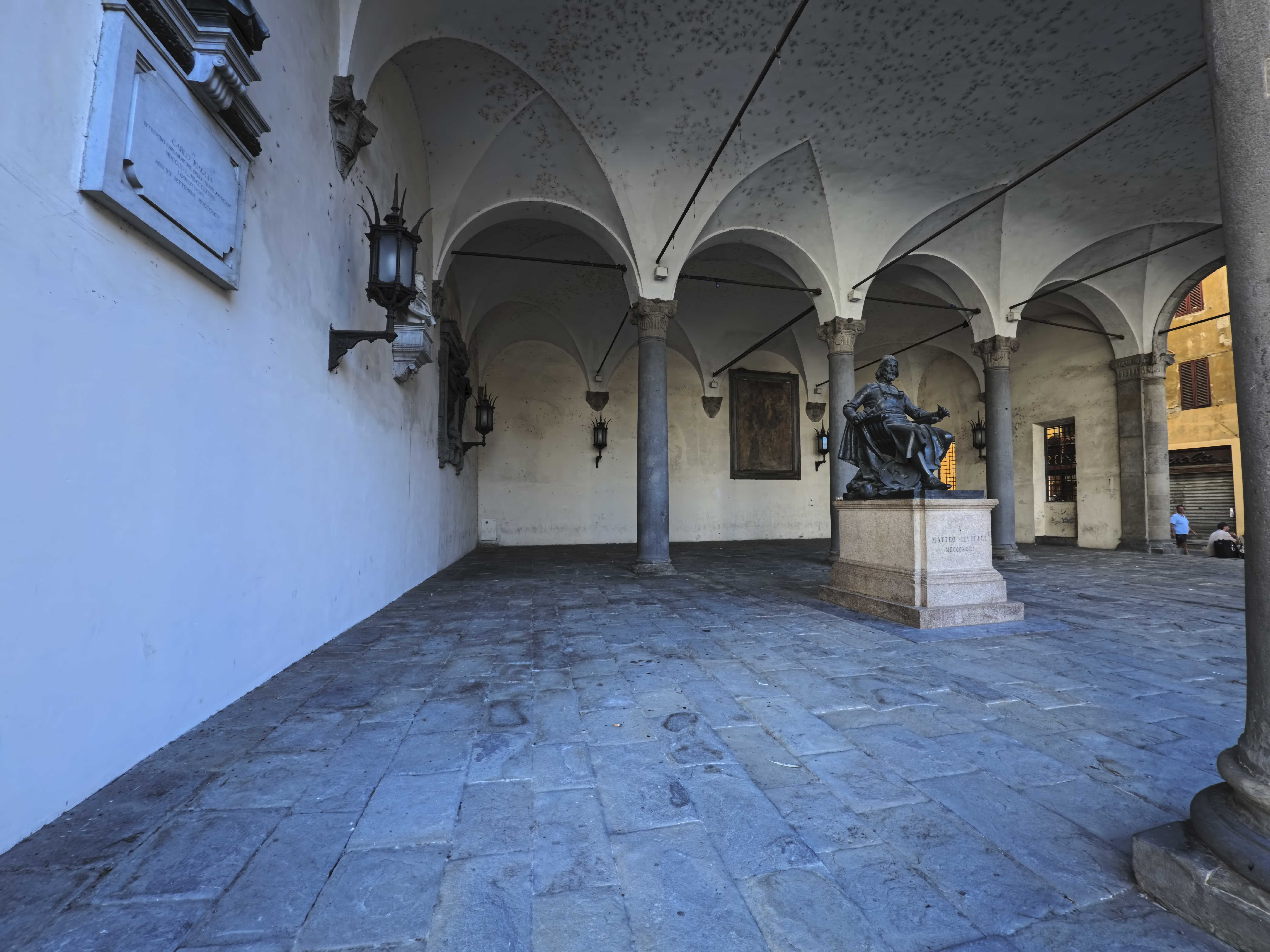 Monumento ottocentesco a Matteo Civitali sotto un loggiato del centro storico di Lucca