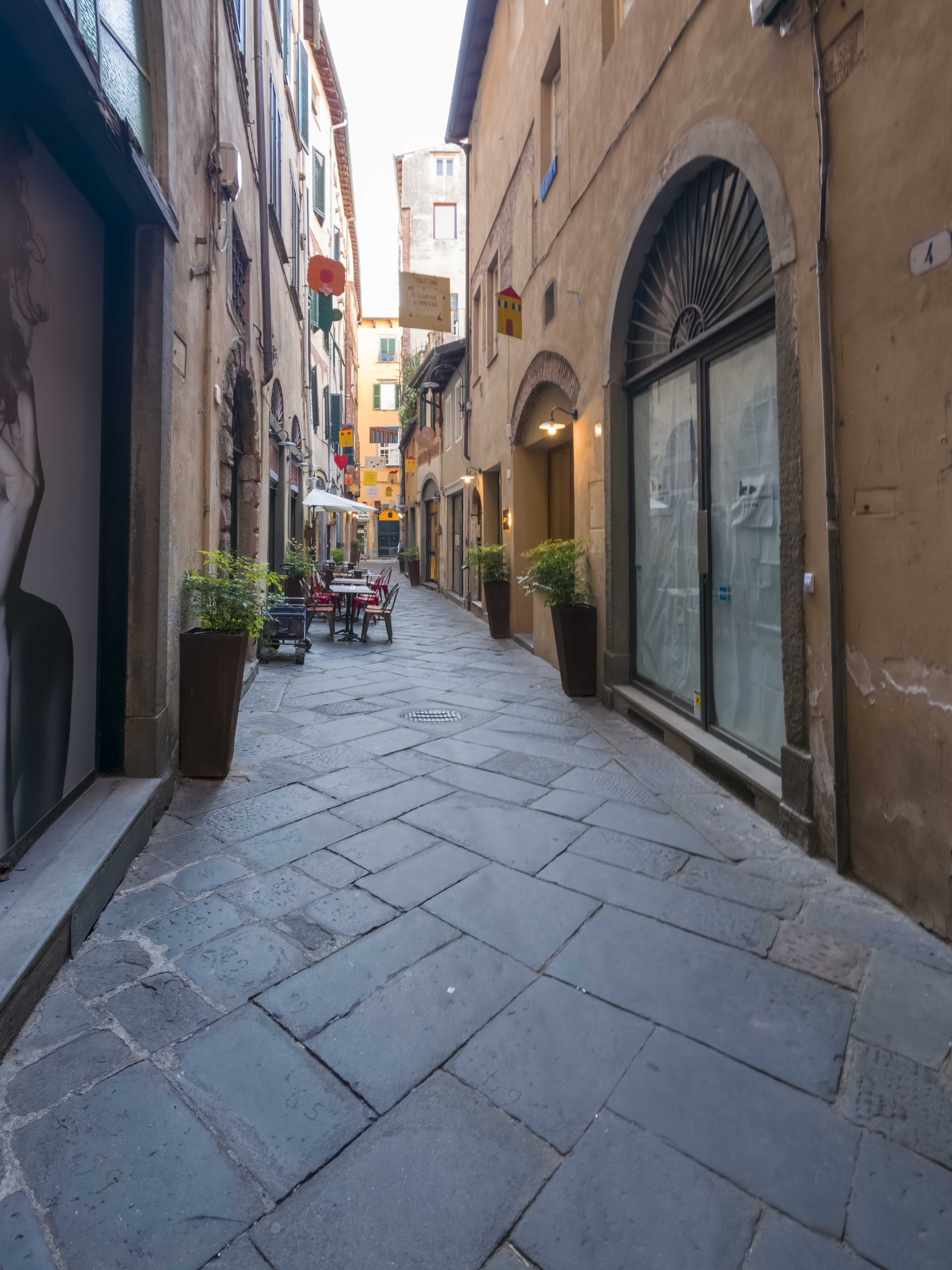 Vicolo del centro storico di Lucca decorato con cartelli colorati e il verso di Ungaretti M'illumino d'immenso
